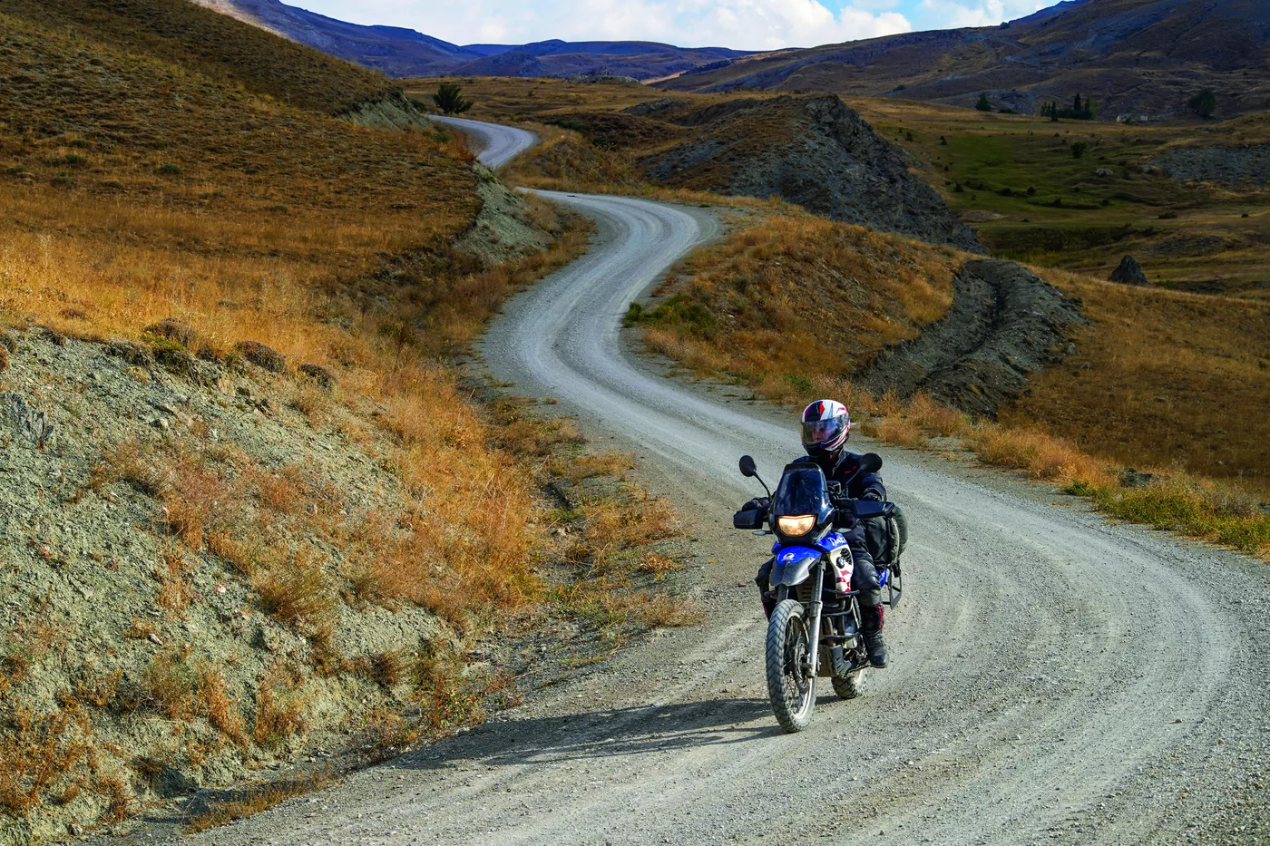Motorrad auf einer geschwungenen Piste durch weite Steppenlandschaft