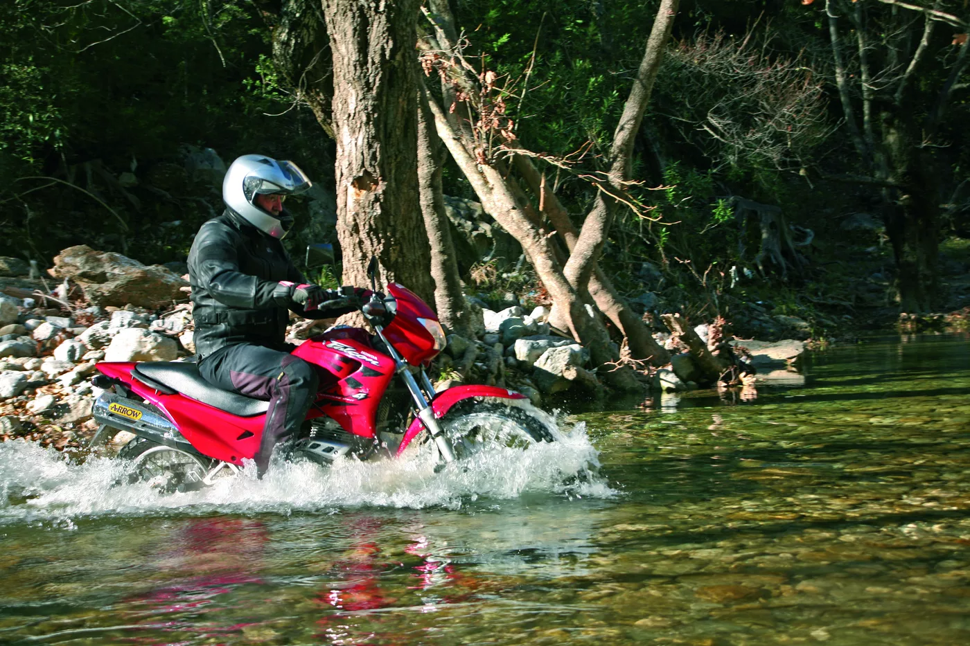 Motorrad durchfährt eine flache Furt im Gebirgsbach Motorrad durchfährt eine flache Furt im Gebirgsbach